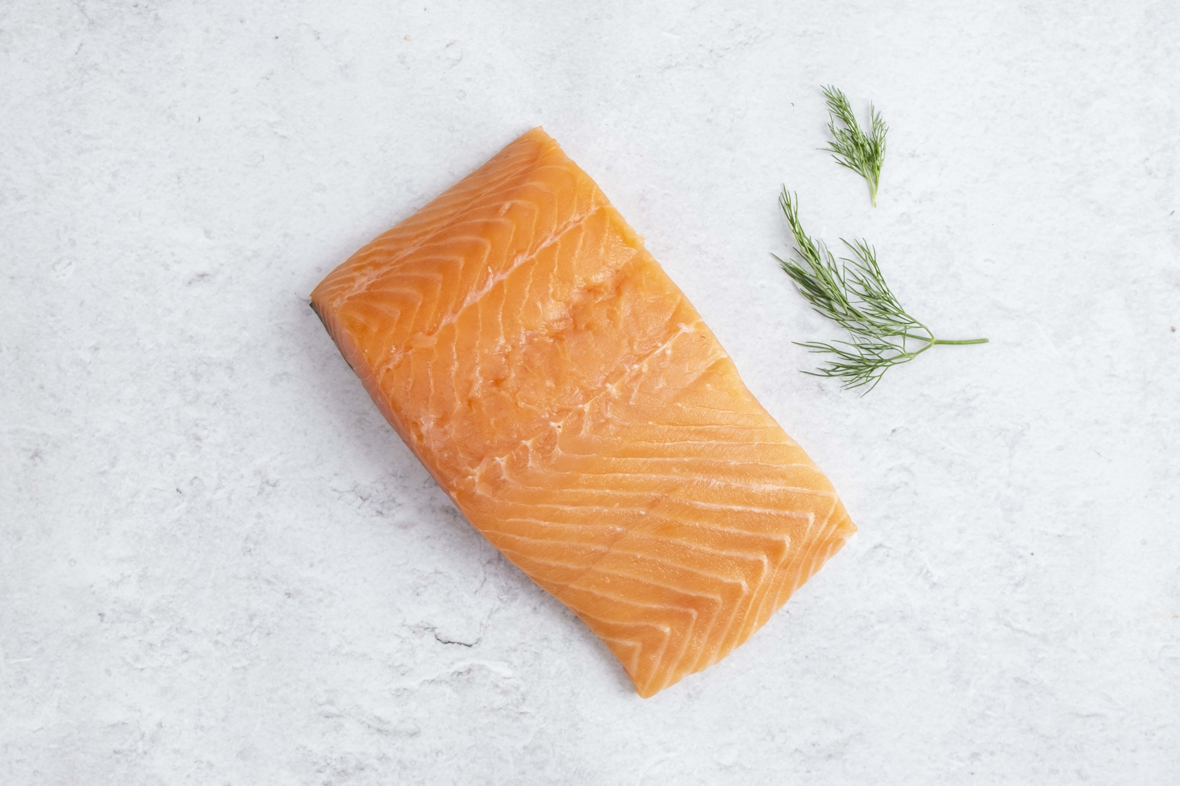 Skinless salmon fillet, raw, on light marble with dill