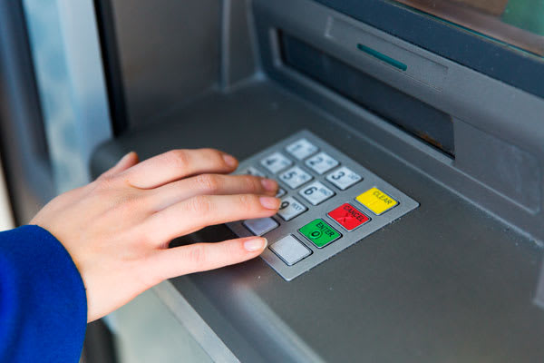 Una persona poniendo el código pin de su tarjeta en un cajero automático