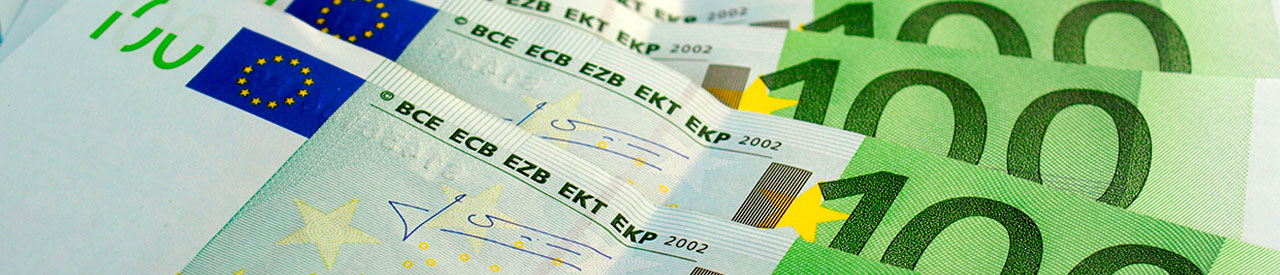 Primer plano de billetes de euro en abanico, con denominaciones de 100 y 50, que muestran los símbolos de la Unión Europea.