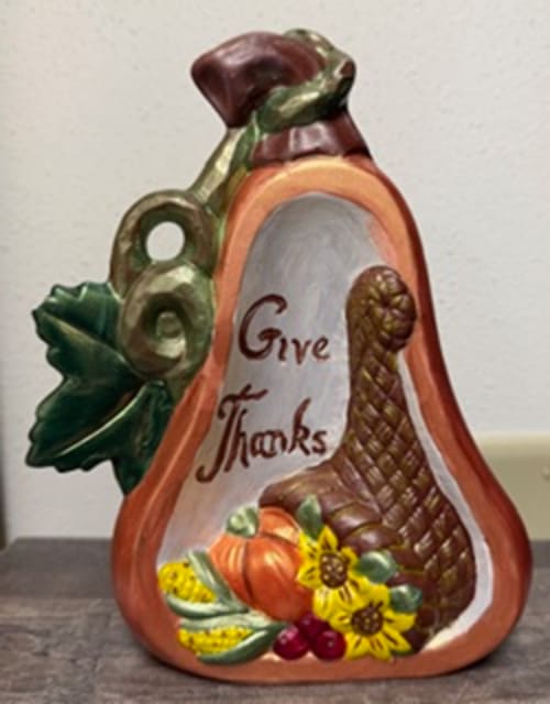 ceramic half gourd. Inside says "Give Thanks". Turkey and other objects inside