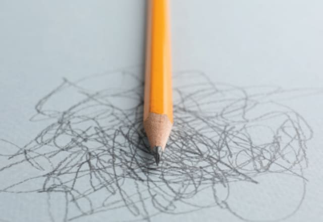 pen laying on a piece of paper that has scribble marks across it