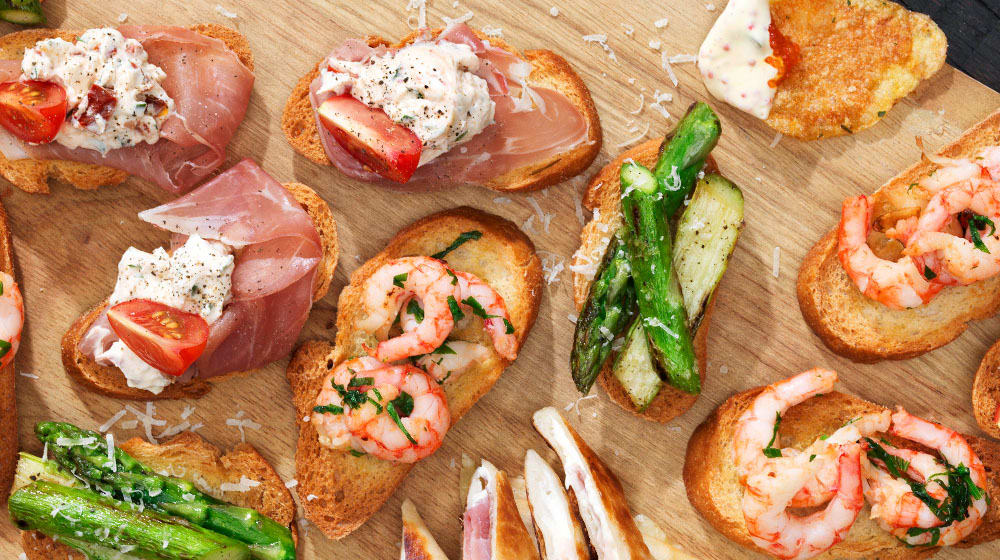 Tapas med prosciutto och färskost, stekta räkor med vitlök och sparris med parmesan