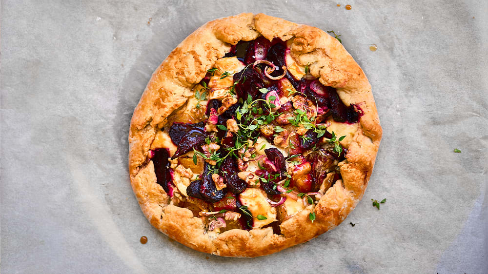 Galette med betor, brie och valnötter på ett bakplåtspapper.