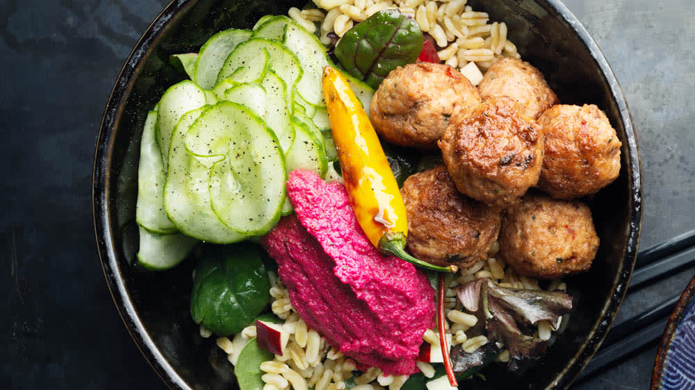 Bowl med heta kycklingbullar picklad gurka och rödbetskräm