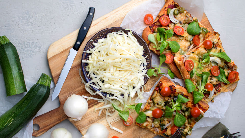 Pizza toppad med färska tomater och machésallad