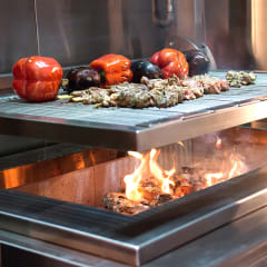 Meat and vegetables grilling on an Asado wood fired grill image