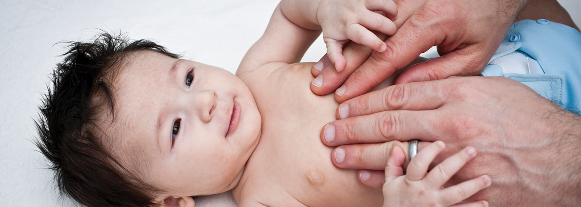 Header Baby - baby laying on back - fathers hands