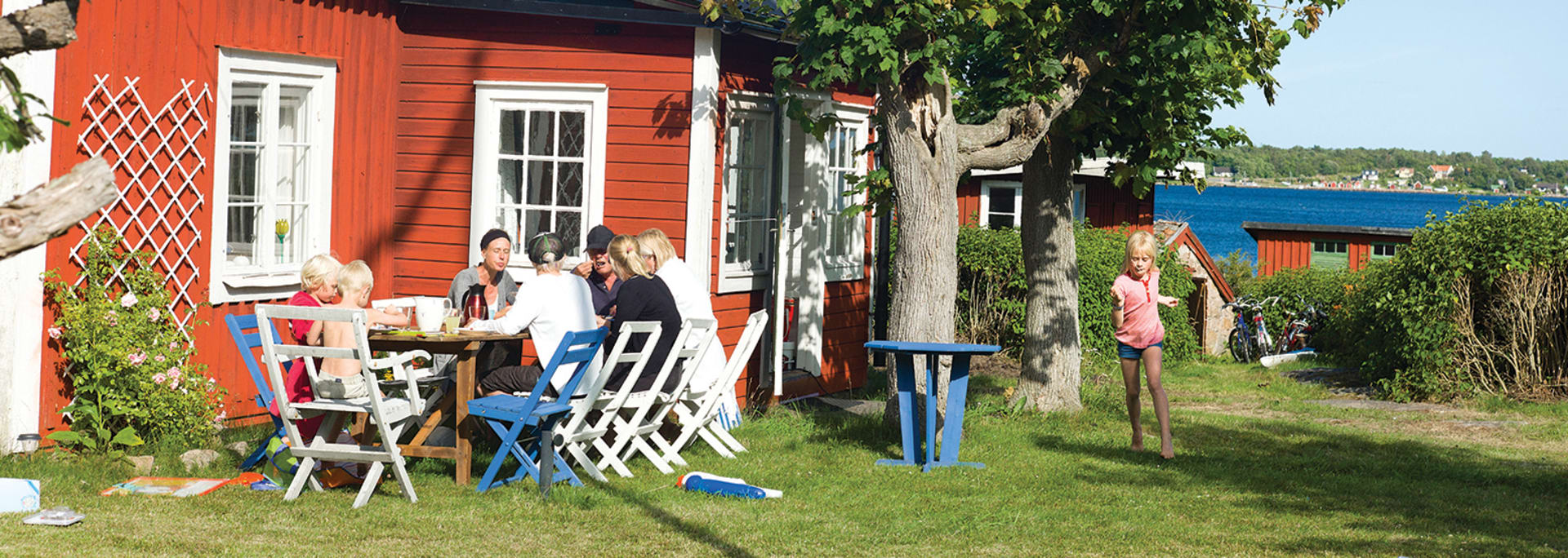 Familj äter frukost vid sommarstugan en solig sommardag