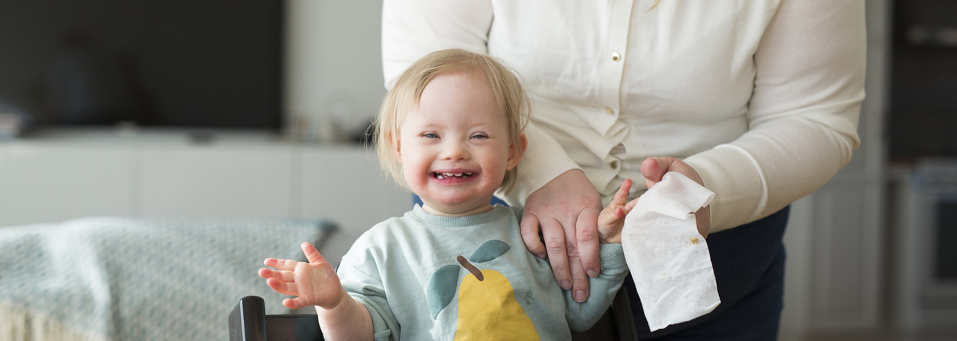 En mamma torkar av händerna på en flicka med Downs syndrom.