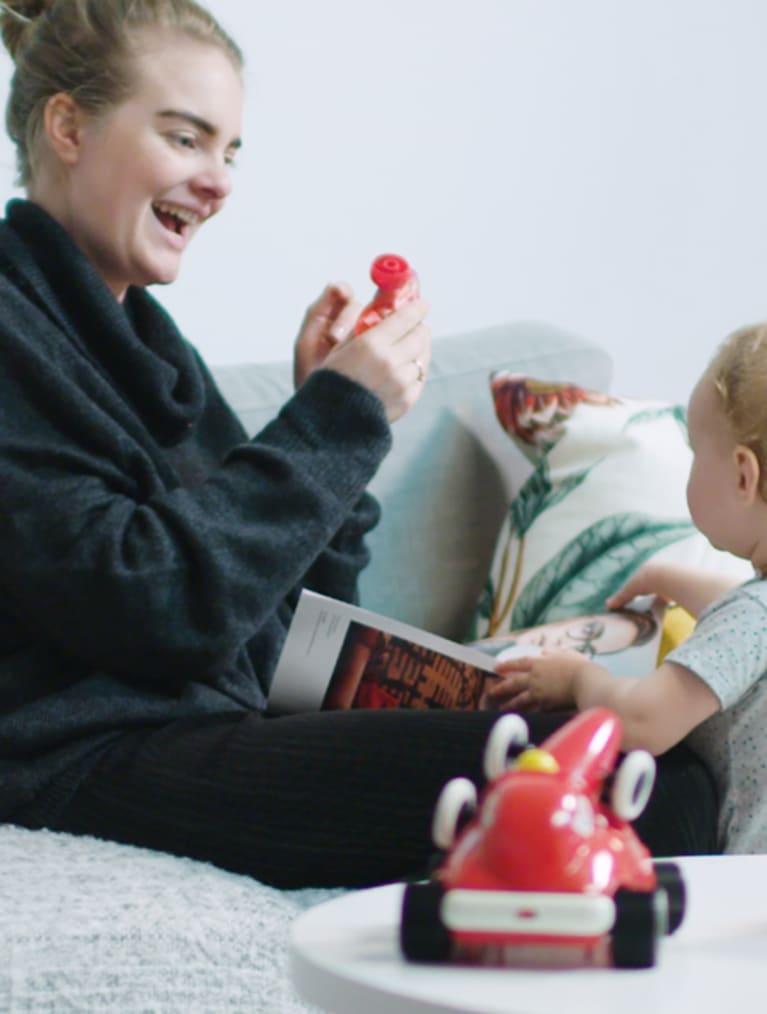 Mamma leker med sitt barn i vardagsrummet