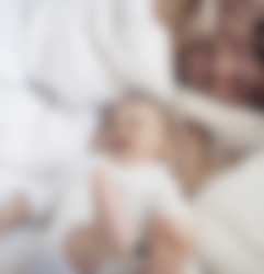 Baby og forælder på en seng