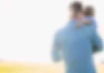 Far med barn der går over en solrig eng