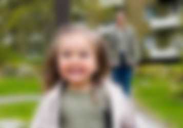 Little kid running, parent in the background