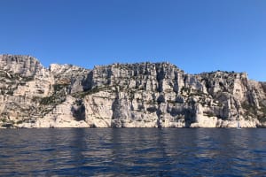 Boat cruising through the Calanques cliffs during a small group tour from Aix-en-Provence