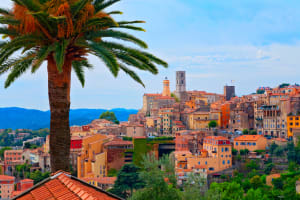 Panoramic view of colourful historic buildings and palm trees in Grasse, France.