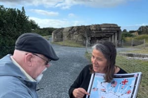 Local guide talking to guests on a D-Day beach with maps in hand