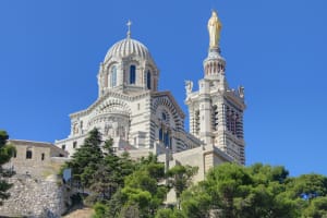 White stone basilica with domes and statue on a hill in Marseille