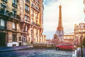 Vintage Citroën 2CV driving along a Paris street with the Eiffel Tower in the background
