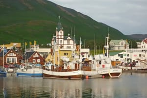 Scenic view of Húsavík harbor with boats and town buildings