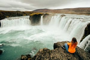 Traveler sitting in front of a large waterfall