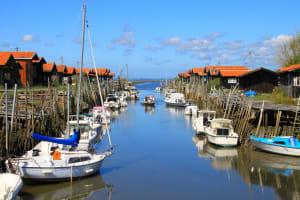 Traditional oyster huts and boats lining a narrow channel on Arcachon Bay
