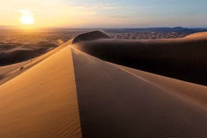 Spectacular sunset over the smooth, sweeping sand dunes of the Sahara Desert during a Marrakech to Merzouga desert tour