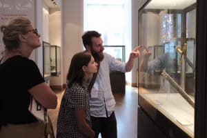 Guide speaking with visitors beside a museum display