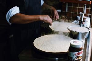 Vendor preparing a crêpe on a hot griddle in Paris