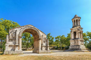 Well‑preserved Roman arch and stone mausoleum surrounded by cypress trees