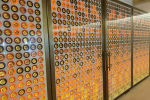 Floor-to-ceiling display of hundreds of gold and amber Château d'Yquem bottle caps mounted on illuminated glass panels inside the château