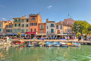 Colorful fishing boats moored in Cassis harbor with pastel houses