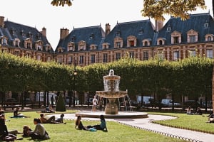 Visitors relaxing by a fountain in Place des Vosges, Paris