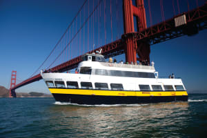 White and yellow ferry boat 'Old Blue' passing under the iconic Golden Gate Bridge in San Francisco Bay