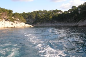 Small boat sailing between white limestone cliffs and turquoise water