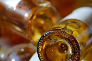 Close-up of the base of golden Sauternes wine bottles with warm amber reflections, Bordeaux