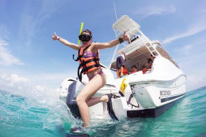 Guest entering the crystal-clear Caribbean Sea from the tour boat for a snorkeling adventure near Isla Contoy.