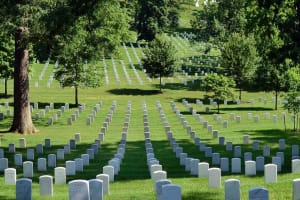 Rows of white grave markers across a green Arlington National Cemetery hillside