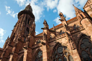 Close up of the red sandstone tower of Freiburg Minster against a blue sky