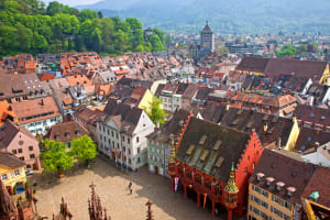 Aerial view over Freiburg rooftops and main square towards forested hills