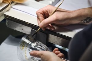 Artisan hand‑paints gold and white motifs on a Saint Louis crystal goblet