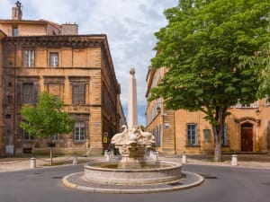 Stone fountain in small square surrounded by historic mansions in Aix-en-Provence