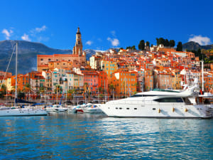 Luxury yacht in Cannes Old Port with Le Suquet old town behind it.