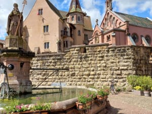 Charming village square with fountain and traditional buildings in Alsace