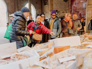 A guide explains seafood inside the Venice Rialto Market.