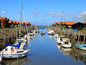 Traditional oyster huts and boats lining a narrow channel on Arcachon Bay