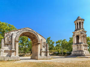 Well‑preserved Roman arch and stone mausoleum surrounded by cypress trees