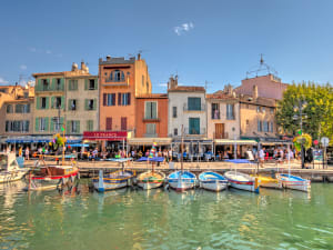 Colorful fishing boats moored in Cassis harbor with pastel houses