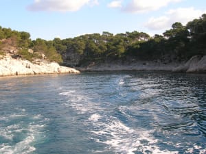 Small boat sailing between white limestone cliffs and turquoise water
