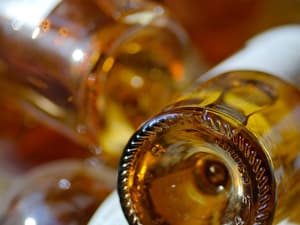 Close-up of the base of golden Sauternes wine bottles with warm amber reflections, Bordeaux