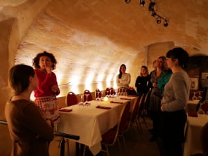 Small group listening to host in softly lit vaulted tasting room in Bordeaux